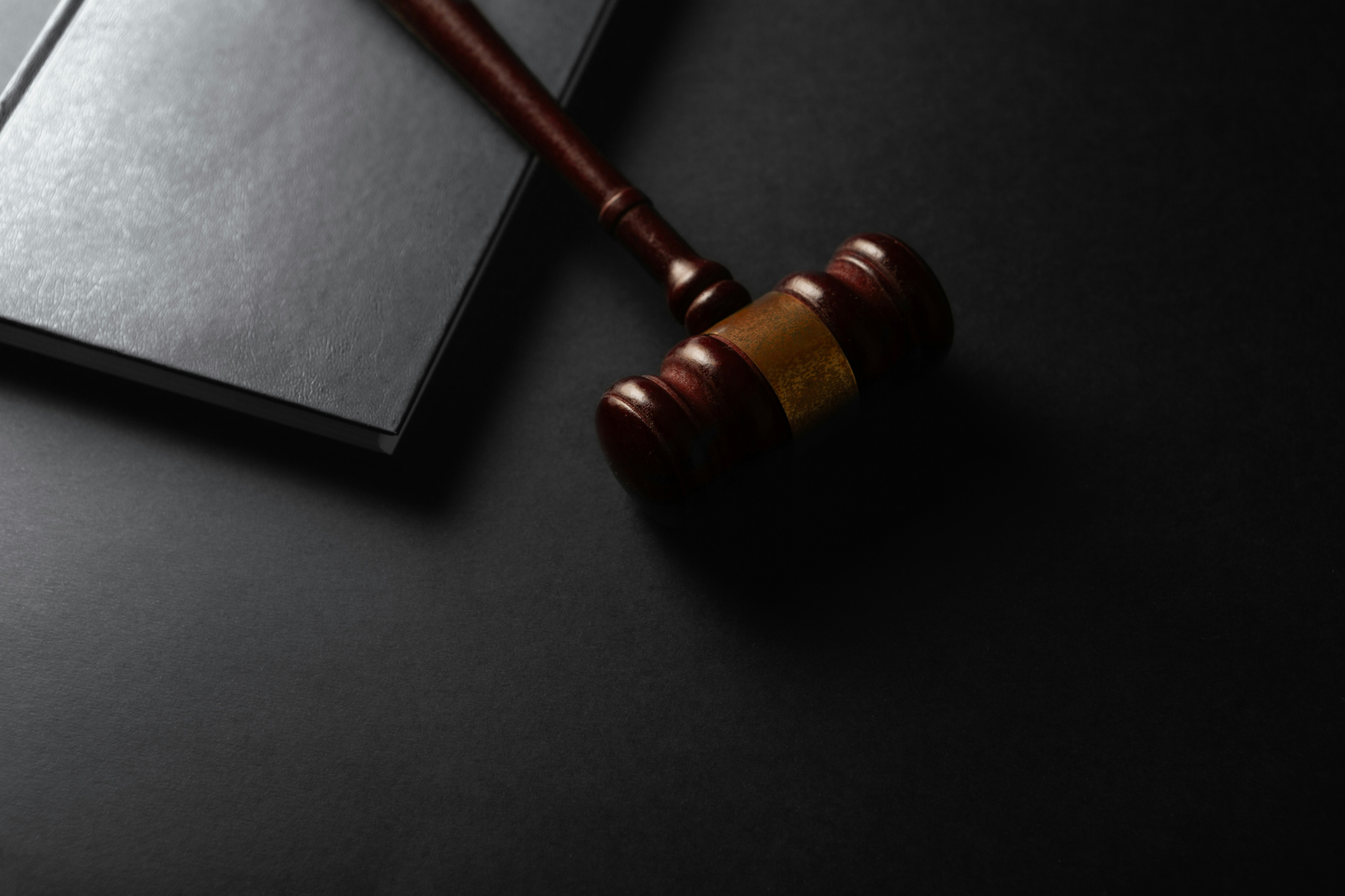 Judge's gavel resting on a dark desk beside a law book